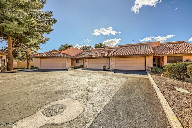 view of front of home with stucco siding, driveway, an attached garage, and a tile roof