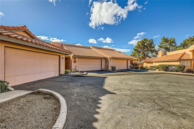 view of front of property with stucco siding, aphalt driveway, and a tile roof