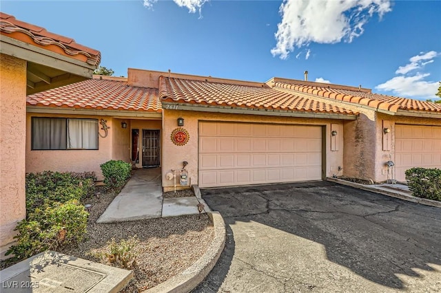 view of front facade featuring aphalt driveway, stucco siding, a tile roof, and a garage