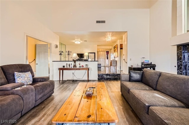 living room with visible vents, a towering ceiling, and wood finished floors