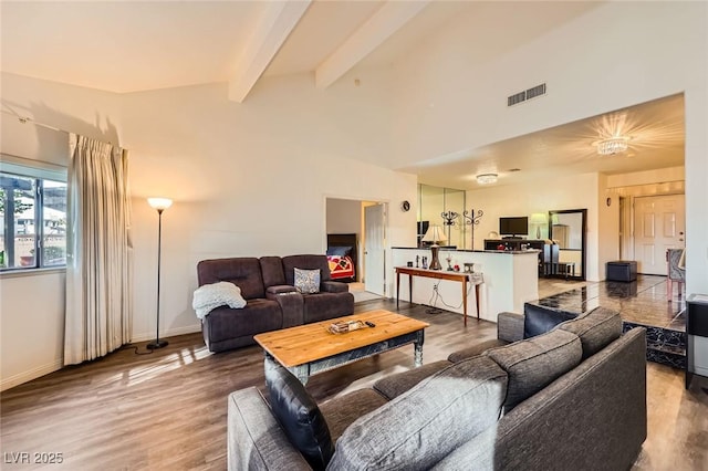 living area featuring lofted ceiling with beams, visible vents, baseboards, and wood finished floors