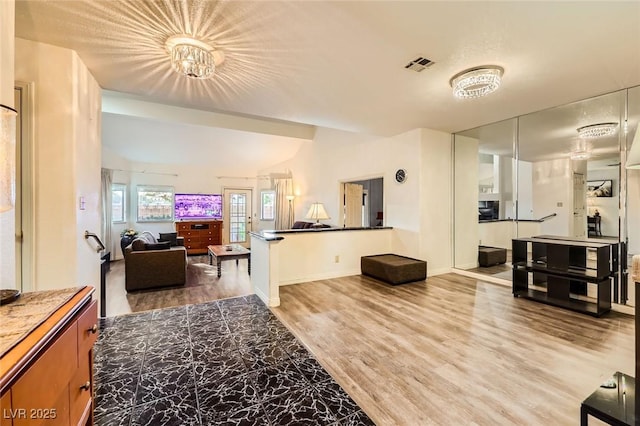 living room with visible vents, baseboards, wood finished floors, and vaulted ceiling