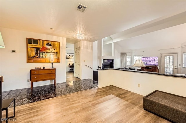 kitchen with visible vents, open floor plan, dark countertops, and wood finished floors