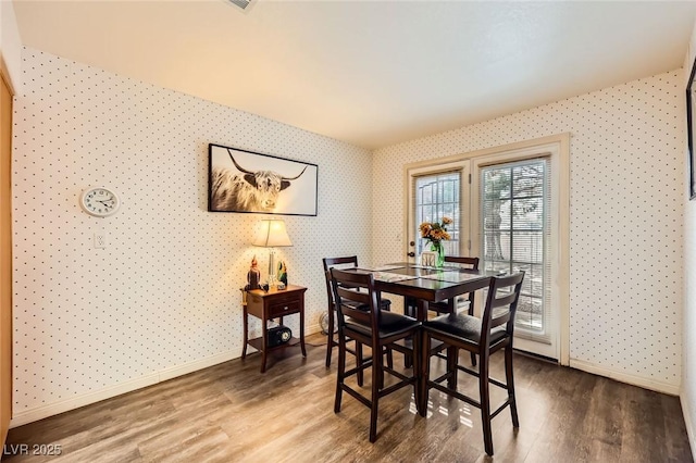 dining room with baseboards, wood finished floors, and wallpapered walls