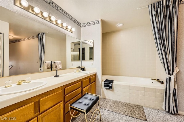 full bathroom with double vanity, tile patterned floors, tiled bath, and a sink