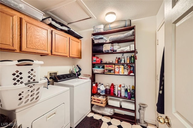 laundry room featuring light floors, washing machine and clothes dryer, attic access, cabinet space, and a textured ceiling