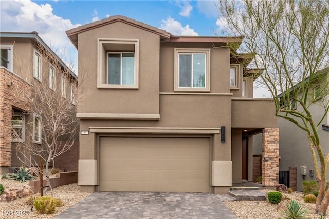 view of front of property featuring stucco siding, a tiled roof, decorative driveway, and a garage