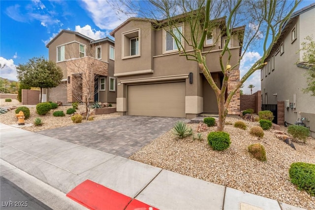 view of front of home with fence, stucco siding, a garage, stone siding, and decorative driveway