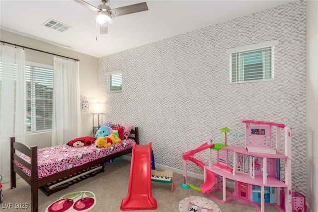 carpeted bedroom featuring visible vents, baseboards, a ceiling fan, and wallpapered walls