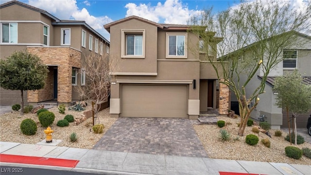 view of front of home with stone siding, stucco siding, decorative driveway, and a garage