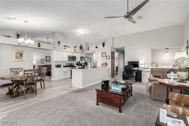 living room with visible vents, ceiling fan with notable chandelier, a textured ceiling, and vaulted ceiling