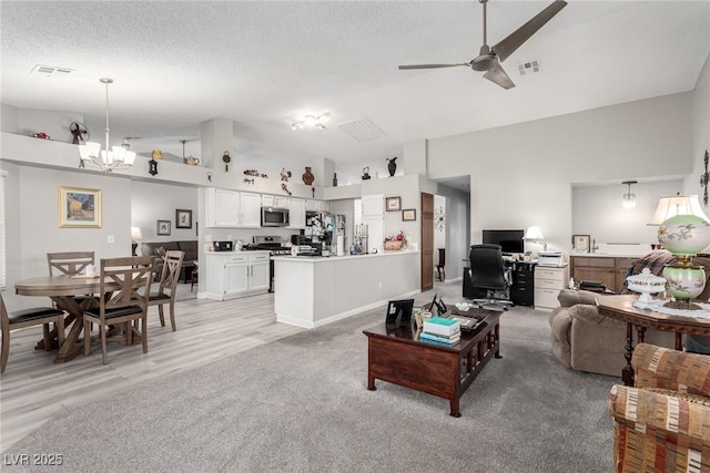 living room with lofted ceiling, ceiling fan with notable chandelier, visible vents, and a textured ceiling