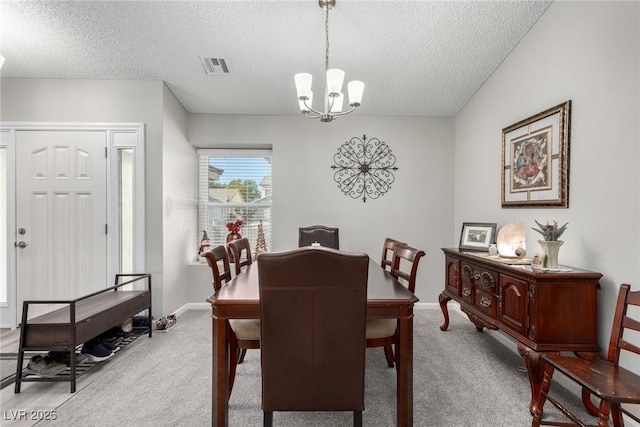 carpeted dining space featuring visible vents, baseboards, a textured ceiling, and an inviting chandelier