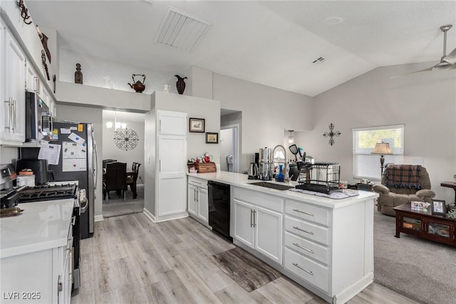 kitchen with a peninsula, a sink, stainless steel appliances, vaulted ceiling, and light countertops