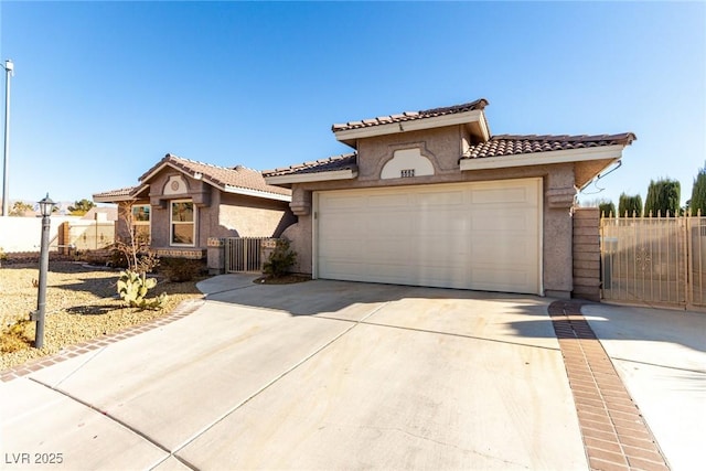 mediterranean / spanish-style house with stucco siding, a tile roof, fence, concrete driveway, and a garage