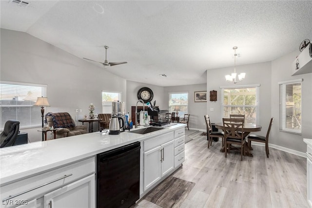 kitchen with a sink, black dishwasher, open floor plan, white cabinetry, and light wood-style floors