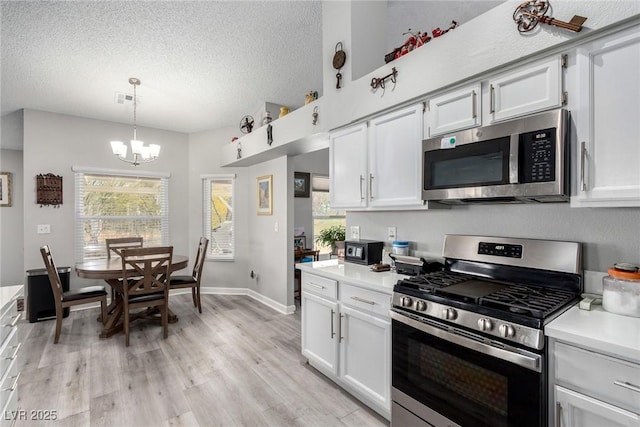 kitchen with visible vents, stainless steel appliances, light countertops, light wood-style floors, and a textured ceiling