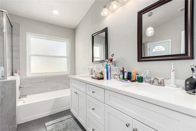 bathroom featuring visible vents, double vanity, a sink, a bathing tub, and a shower