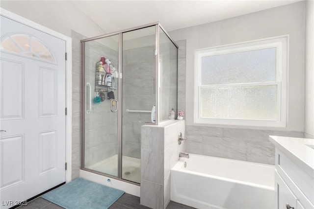 full bathroom featuring vanity, a shower stall, and a washtub