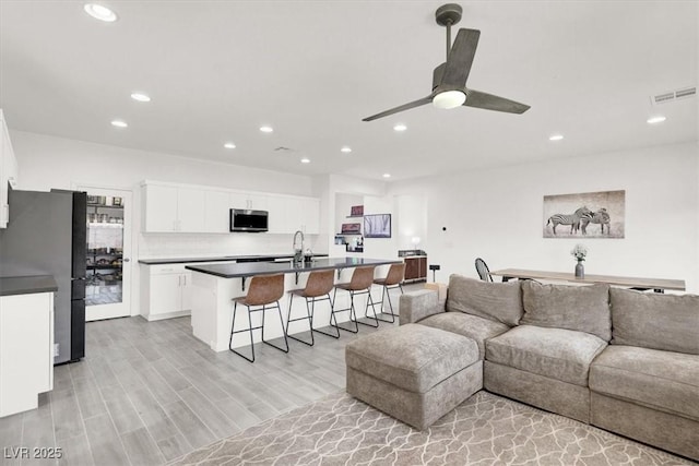 living room featuring recessed lighting, visible vents, light wood-style flooring, and a ceiling fan