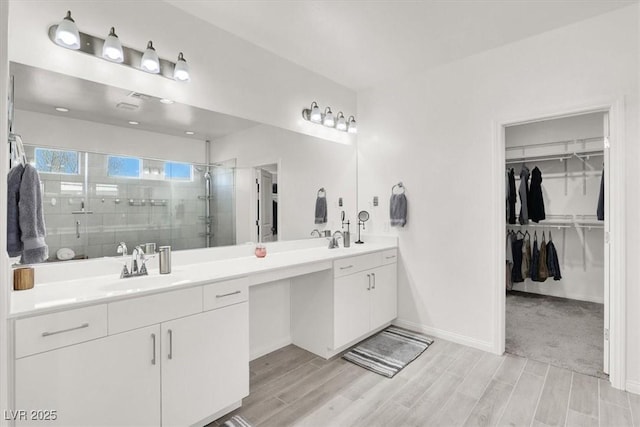 bathroom with double vanity, wood finish floors, a stall shower, and a sink