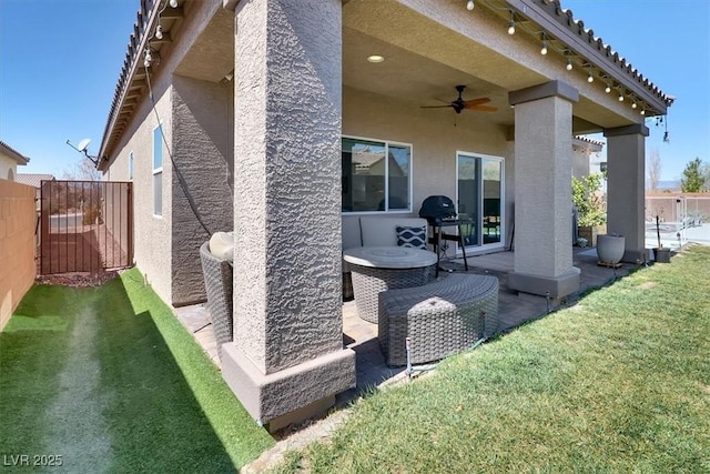 exterior space with stucco siding, a patio, a ceiling fan, and fence