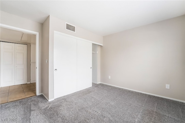 unfurnished bedroom with carpet flooring, baseboards, visible vents, and a closet