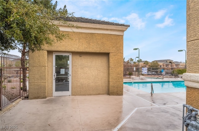 community pool with a patio and fence