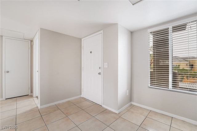 entryway with light tile patterned flooring and baseboards