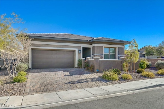 prairie-style house featuring a fenced front yard, stucco siding, decorative driveway, and a garage