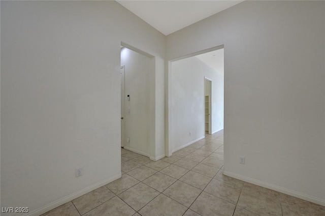 spare room featuring light tile patterned floors and baseboards