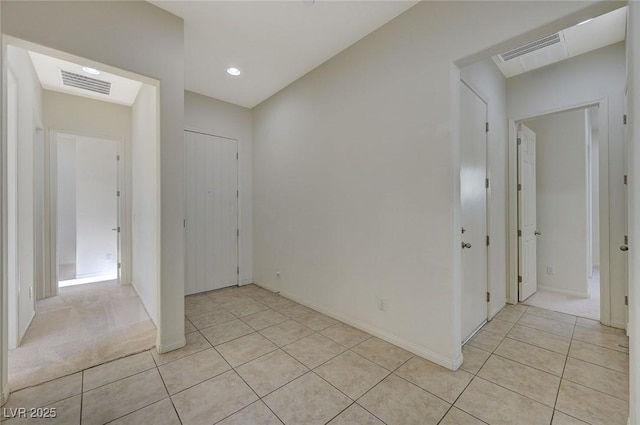 empty room featuring light tile patterned flooring, visible vents, and baseboards