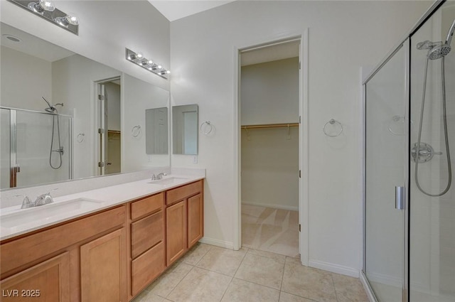 full bath with double vanity, a stall shower, a sink, a spacious closet, and tile patterned floors