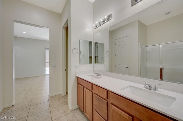 bathroom with a sink, a shower with door, double vanity, and tile patterned floors