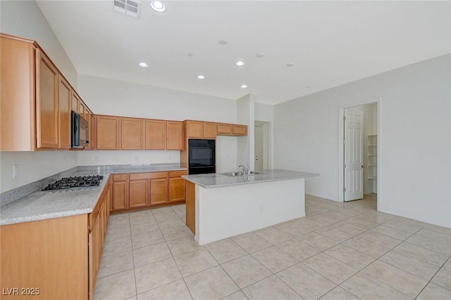 kitchen with visible vents, black appliances, a center island with sink, a sink, and light tile patterned flooring