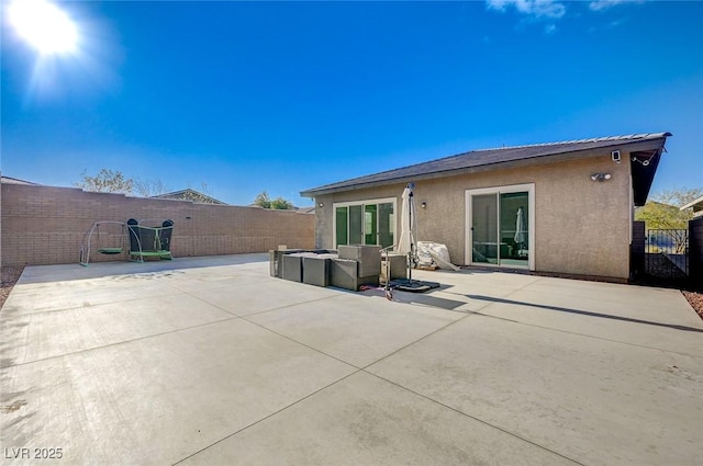 rear view of house featuring a patio area, stucco siding, outdoor lounge area, and fence