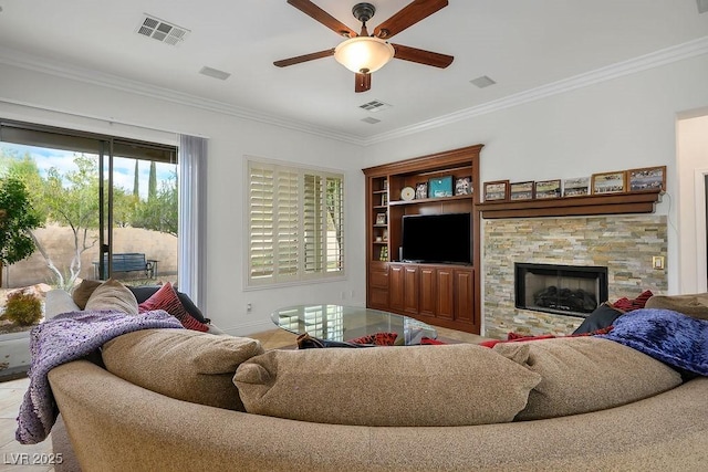 living room featuring visible vents, a stone fireplace, crown molding, and a ceiling fan