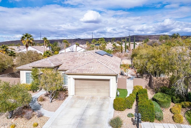 view of front facade with fence, stucco siding, concrete driveway, a garage, and a mountain view