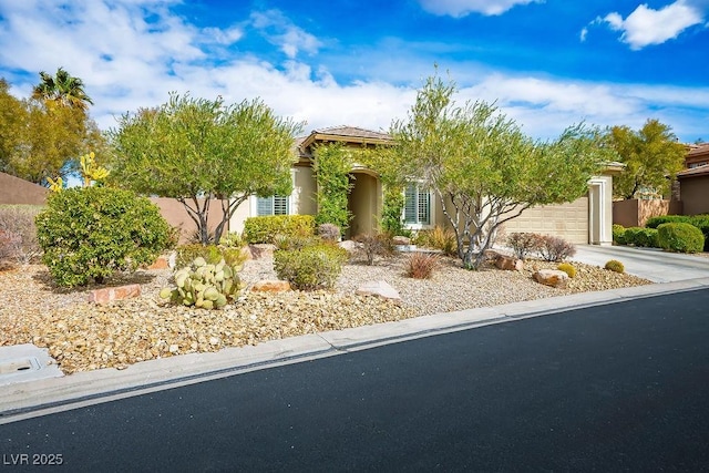 view of front of property featuring stucco siding, driveway, an attached garage, and fence