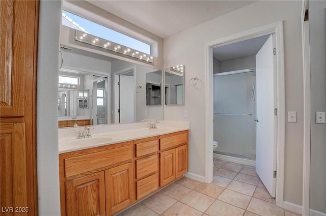 bathroom featuring tile patterned flooring, toilet, a stall shower, and a sink