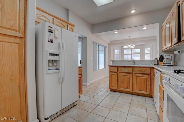 kitchen with light countertops, a peninsula, light tile patterned flooring, white appliances, and a sink