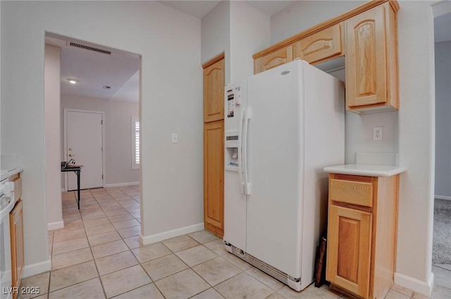 kitchen featuring light countertops, visible vents, white fridge with ice dispenser, and light brown cabinetry