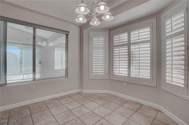 empty room featuring a notable chandelier, light tile patterned flooring, and baseboards