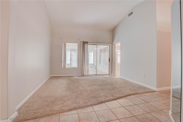 empty room with light tile patterned floors, visible vents, light colored carpet, and baseboards