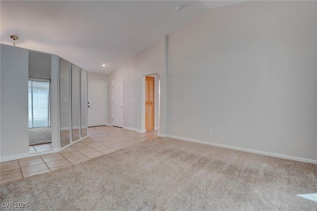 spare room with light carpet, baseboards, lofted ceiling, and light tile patterned flooring