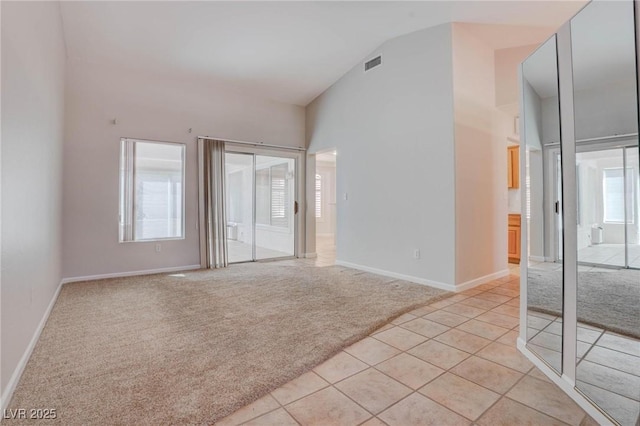 unfurnished bedroom with access to exterior, visible vents, baseboards, light carpet, and high vaulted ceiling