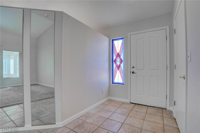 foyer entrance with light tile patterned floors, light colored carpet, and baseboards