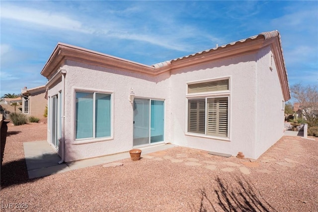 rear view of house featuring stucco siding