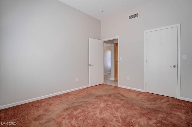 unfurnished bedroom featuring a high ceiling, baseboards, visible vents, and carpet floors