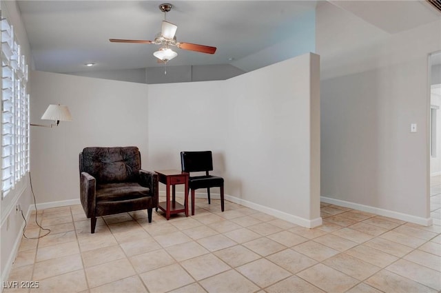 living area featuring baseboards, lofted ceiling, light tile patterned flooring, and a ceiling fan